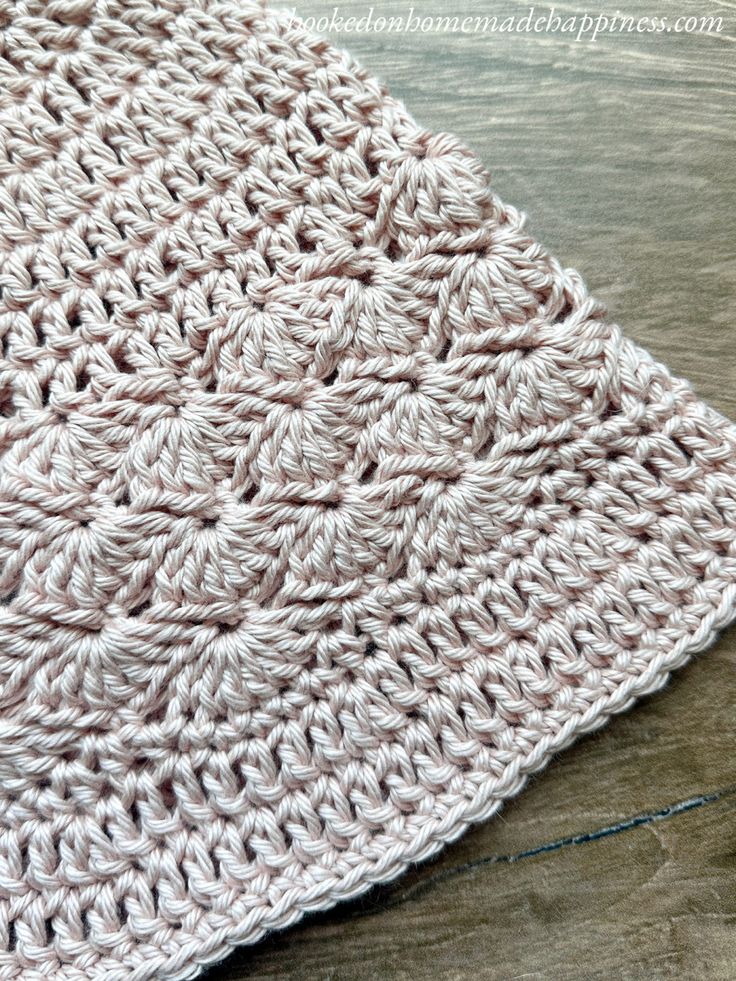 a crocheted dishcloth is laying on a wooden surface