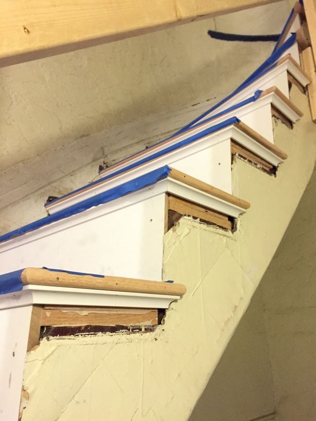 an unfinished stair case with blue tape on the top and bottom edge, in front of a white wall