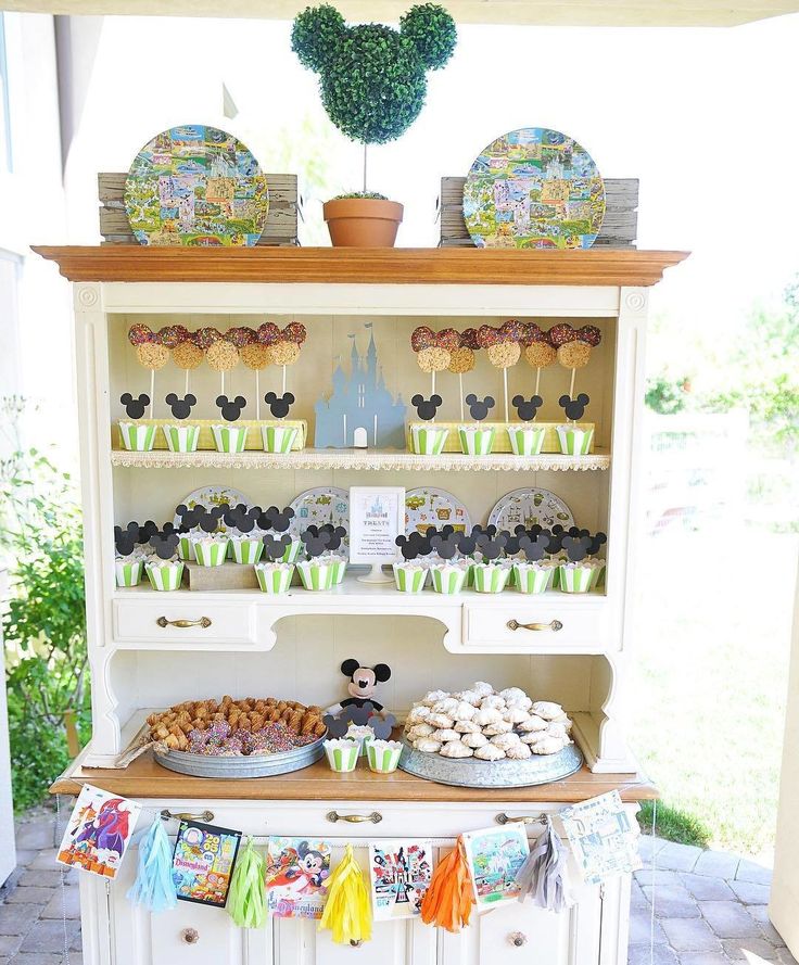 a display case filled with cupcakes and muffins next to a potted plant