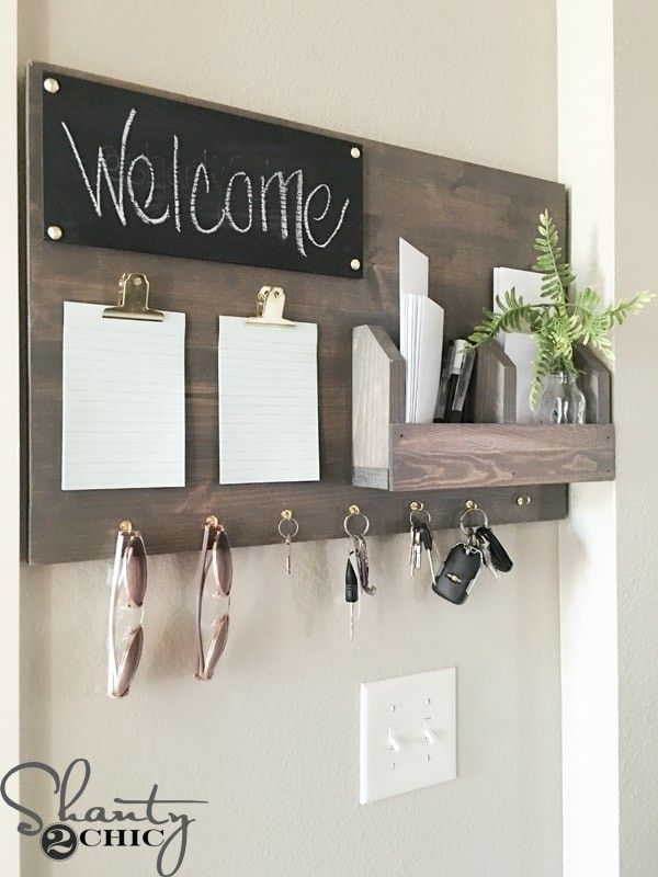 a wooden sign that says welcome hanging on a wall with keys and notepads