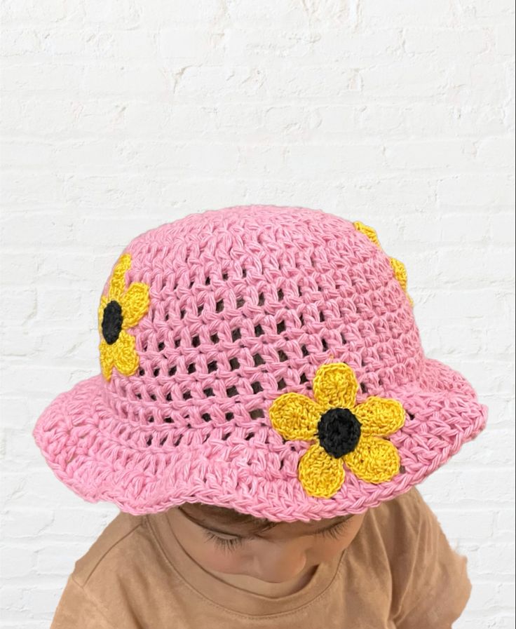 Pink crochet bucket hat with crochet sunflowers all made by hand. 12-18months #crochethatpattern #sunflower #buckethatsoutfit #pink #daisies #buckethat #crochetdesign #etsygifts #crochetforbaby #fashion #crochetclothes #blackownedbusiness #ecofriendlyfashion Spring Beach Crochet Hat With Flower Shape, Summer Crochet Cap Made Of Cotton Yarn, Handmade Flower Hats For Summer, Adjustable Cotton Yarn Crochet Cap, Hand Knitted Mini Cap For The Beach, Handmade Yarn Bucket Hat For Spring, Spring Beach Mini Hats Made Of Yarn, Spring Knitted Cotton Yarn Hats, Adjustable Crochet Hat Cap