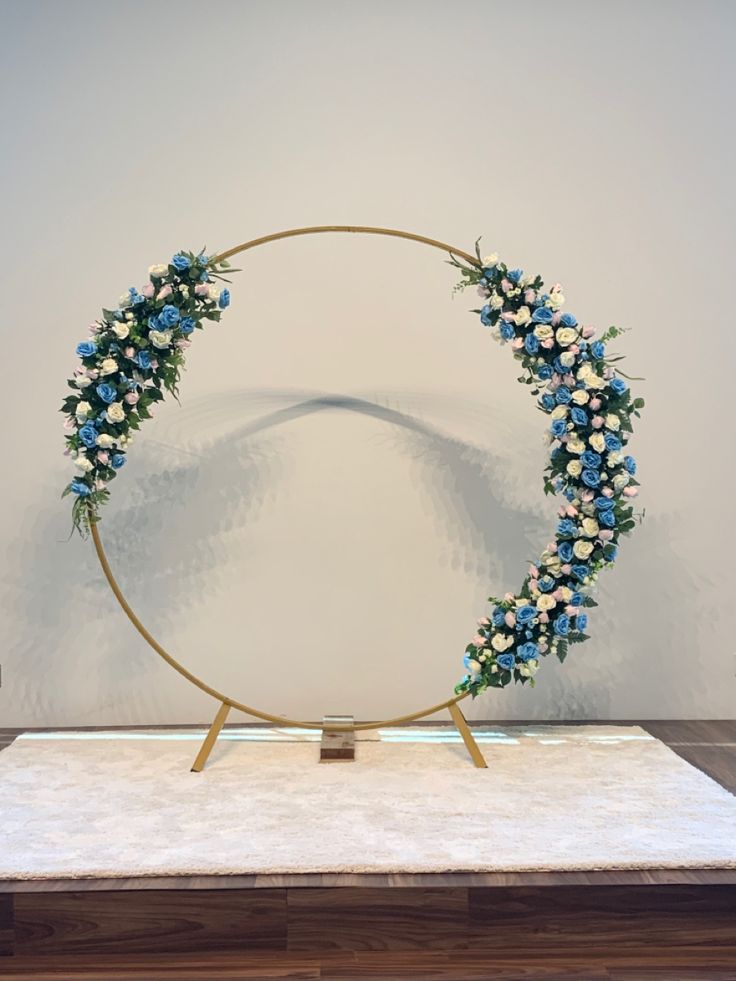 a circular display with blue and white flowers on it's side, in front of a wall