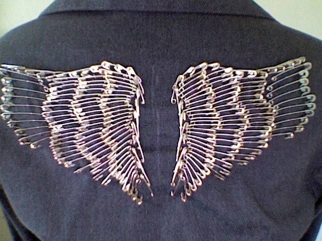 the back of a woman's jacket with metal wings on it, and gold thread