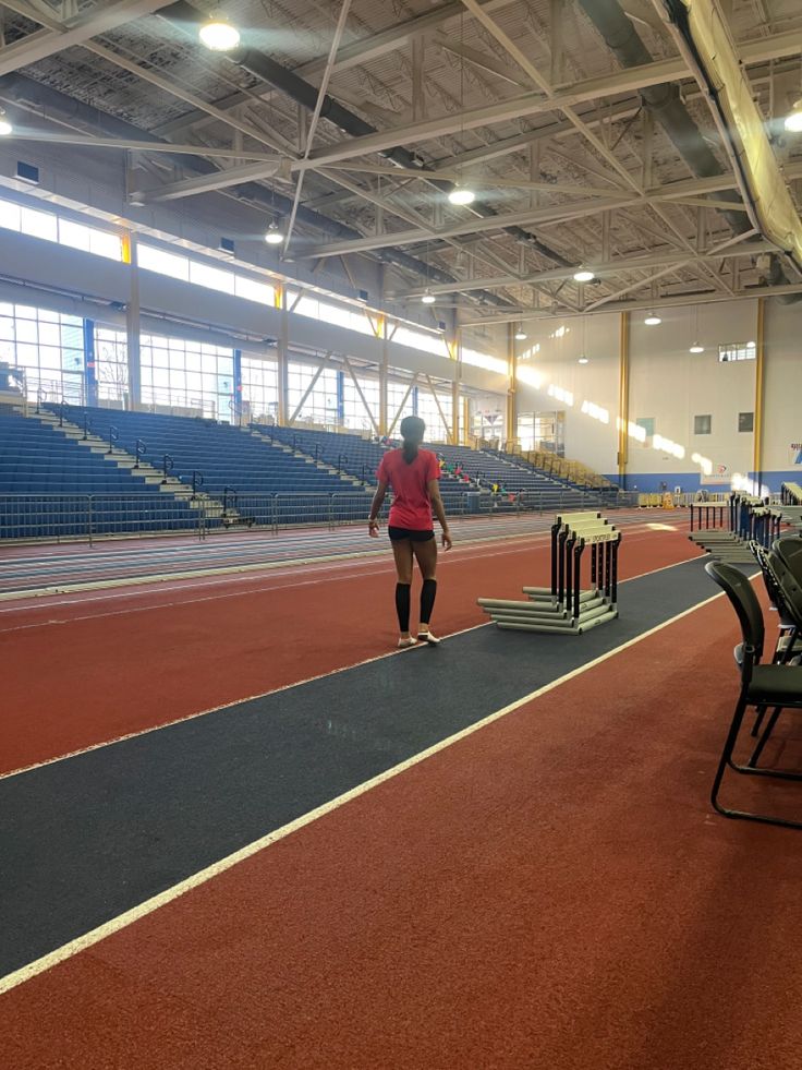 a woman is walking on the tennis court with her racket in hand and some chairs to the side