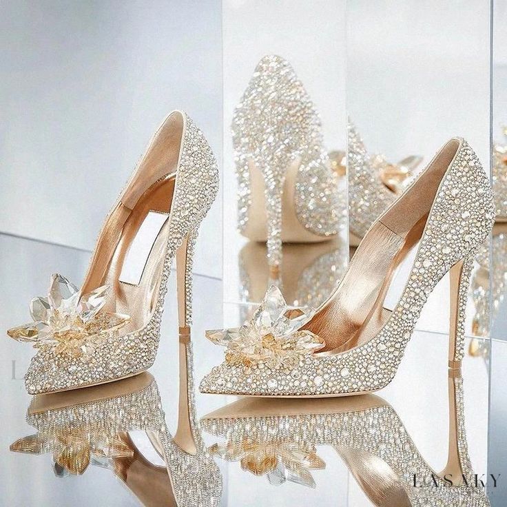 a pair of high heeled shoes with pearls and bows on the heels are shown in front of a mirror