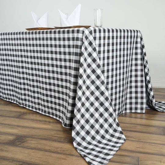 a black and white checkered tablecloth with napkins on it sitting on a wooden floor