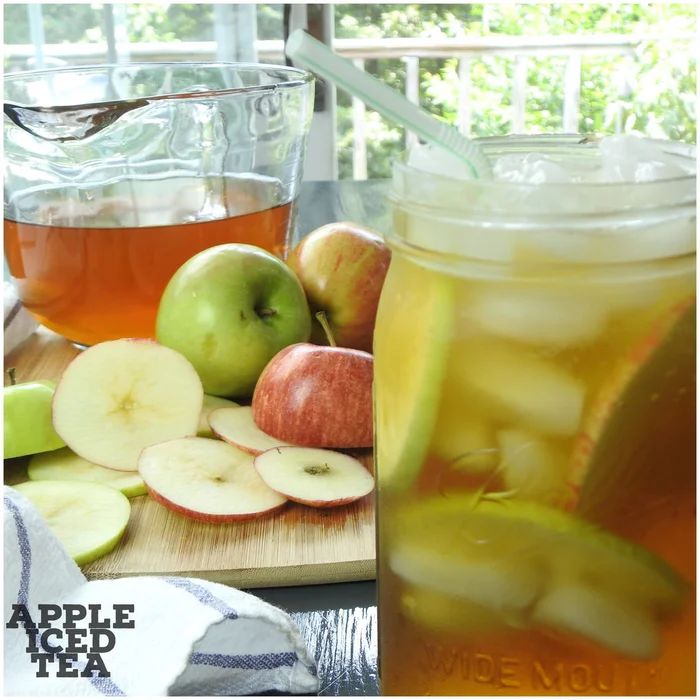 there is a pitcher of apple cider next to apples and sliced apples on a cutting board