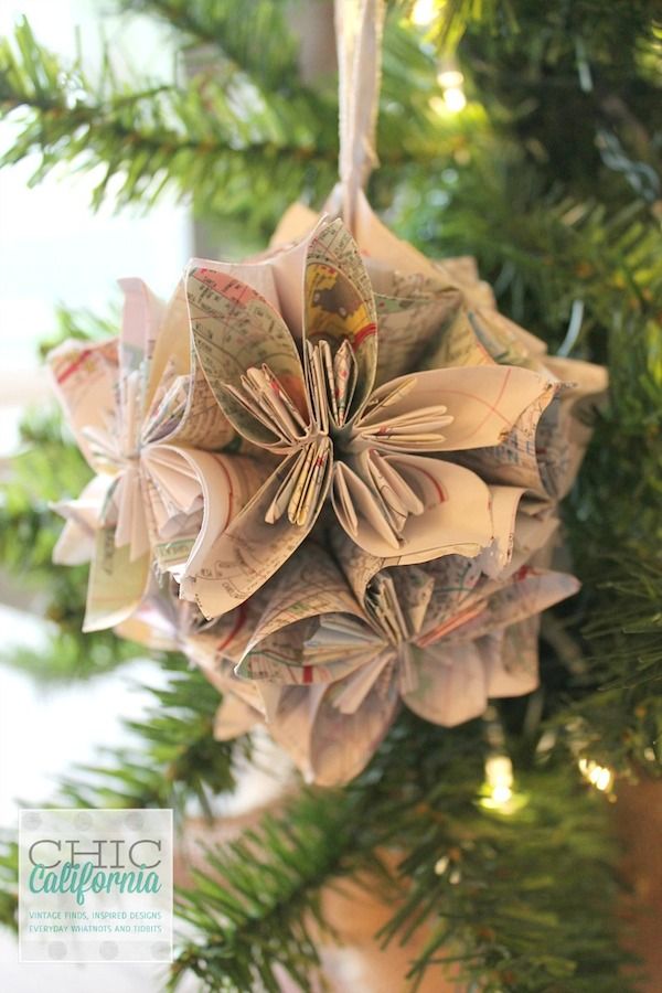 an ornament hanging from a christmas tree decorated with rolled up paper flowers and ribbons