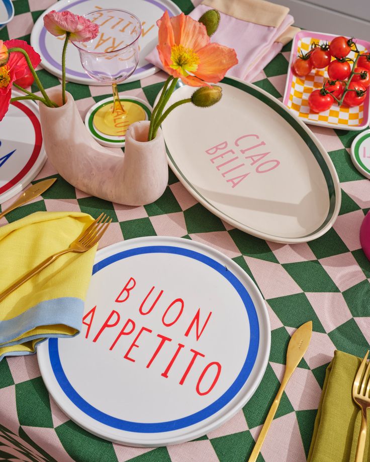 a table topped with plates and utensils on top of a checkered table cloth