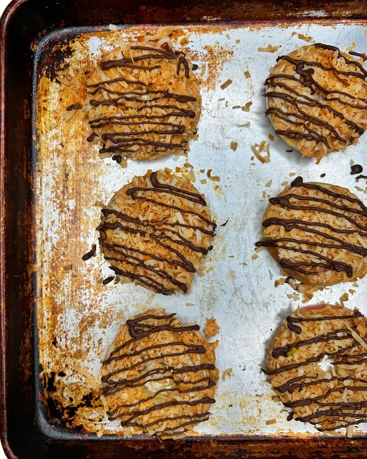 six cookies with chocolate drizzled on them sitting in a baking pan, ready to be baked