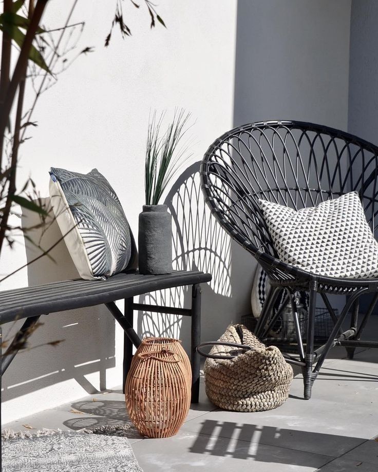 two wicker chairs sitting next to each other on top of a cement floor near plants