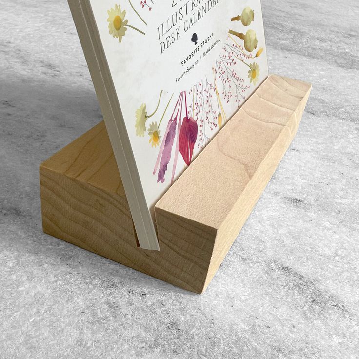 an open book is sitting on top of a wooden stand in the middle of concrete