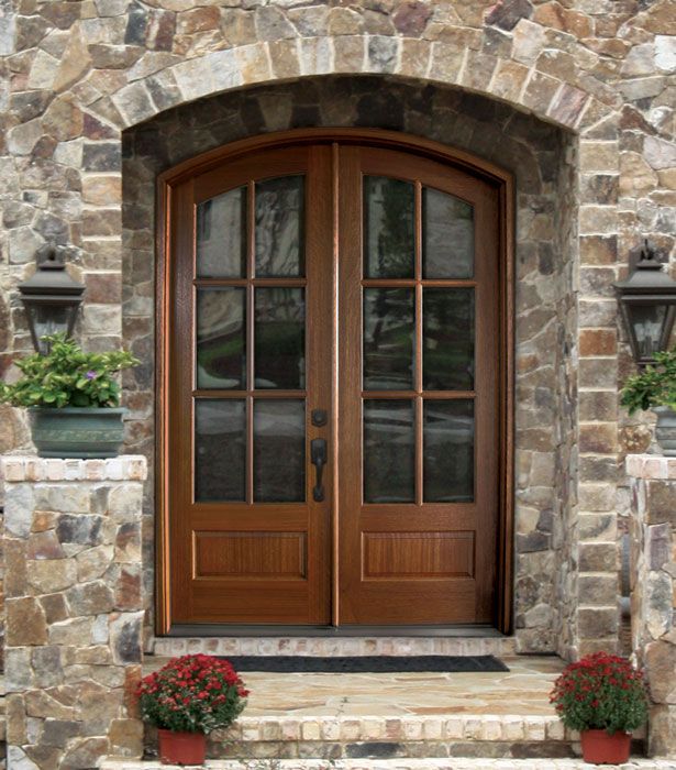 a stone house with two double doors and flower pots