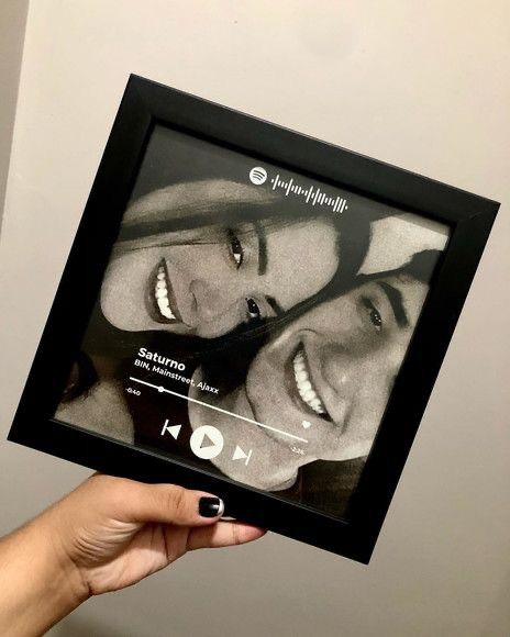 a person holding up a framed photo with two smiling women on it's face