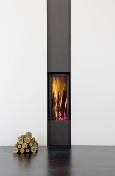 a fire place with logs on the floor next to it and a white wall in the background