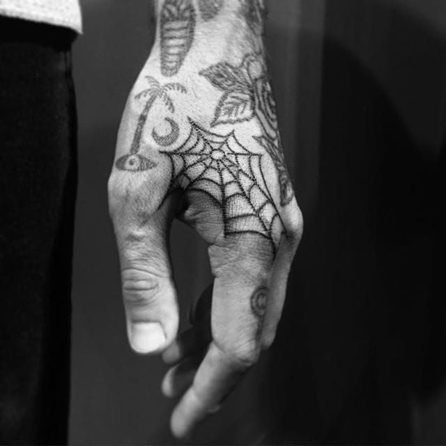 a person with a spider web tattoo on their hand