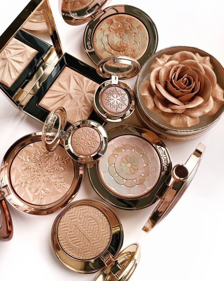 many different types of cosmetics are arranged on a white surface with a rose in the middle