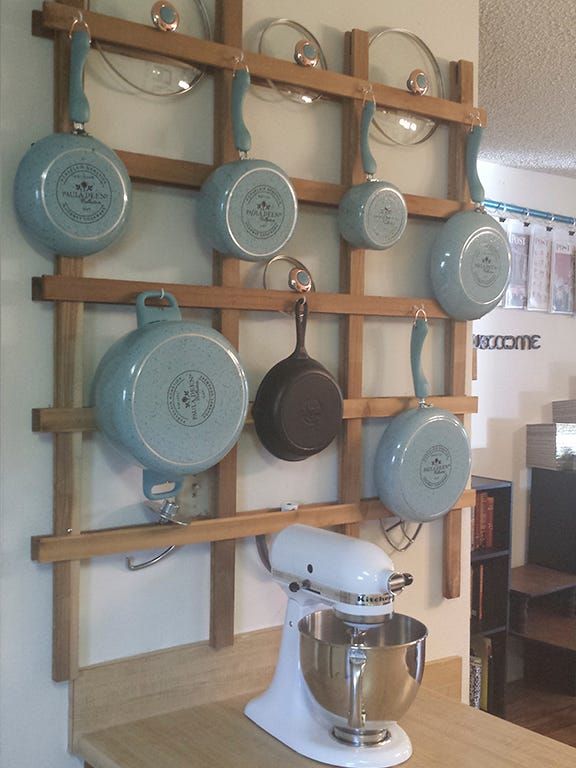 pots and pans are hanging on the wall in front of an electric mixer,