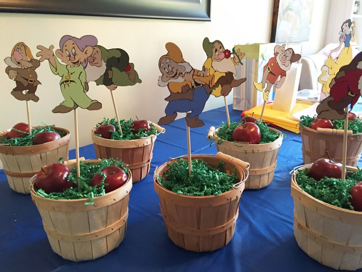 apples in wooden baskets on a blue table cloth with paper cutouts depicting cartoon characters