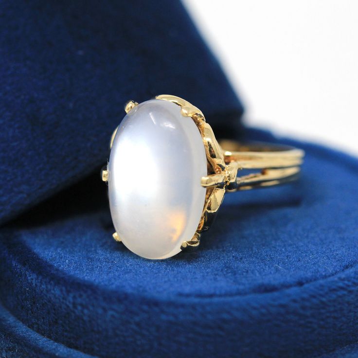 Magical vintage circa 1980s 14k yellow gold genuine moonstone ring! This gorgeous statement ring features an oval cabochon moonstone weighing an estimated 9.61 carats. There is a substantial setting adorned with open metal work along the ring galleries and shoulders. An enchanting piece of fine estate jewelry showcasing a beautiful genuine gemstone! *Sale - price reduced from $1100 USD to $1090 USD.  ERA - Circa 1980s  METAL / MATERIAL - 14k yellow gold, genuine moonstone (approx. 9.61 CT) MARKINGS / HISTORY - N/A, professionally tested CONDITION - Good estate condition, with age consistent wear. Yellow gold metal has been professionally polished & cleaned. Genuine moonstone secure with light surface wear (abrasion). Age appropriate patina & wear remains. Amazing vintage moonstone ring!  S Luxury Vintage Moonstone Ring In Oval Cabochon, Luxury Vintage Yellow Gold Moonstone Ring, Luxury Vintage Moonstone Ring For A Gift, Collectible Oval Cabochon Moonstone Ring, Yellow Gold Oval Cabochon Moonstone Ring, Heirloom Oval Moonstone Ring, Classic Formal Cabochon Moonstone Ring, Classic Yellow Gold Oval Cabochon Moonstone Ring, Antique Oval Moonstone Ring Collectible