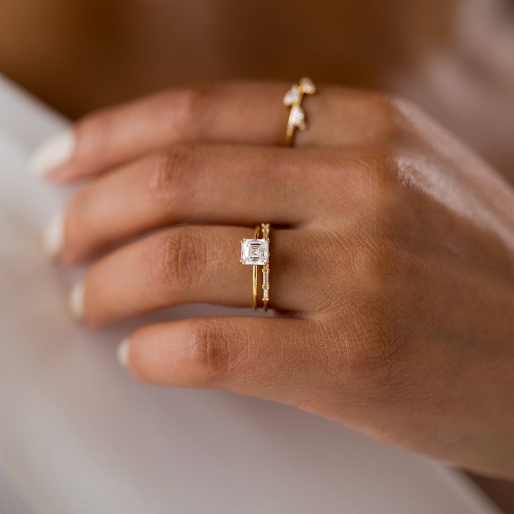 a woman's hand with two gold rings and a diamond ring on her finger