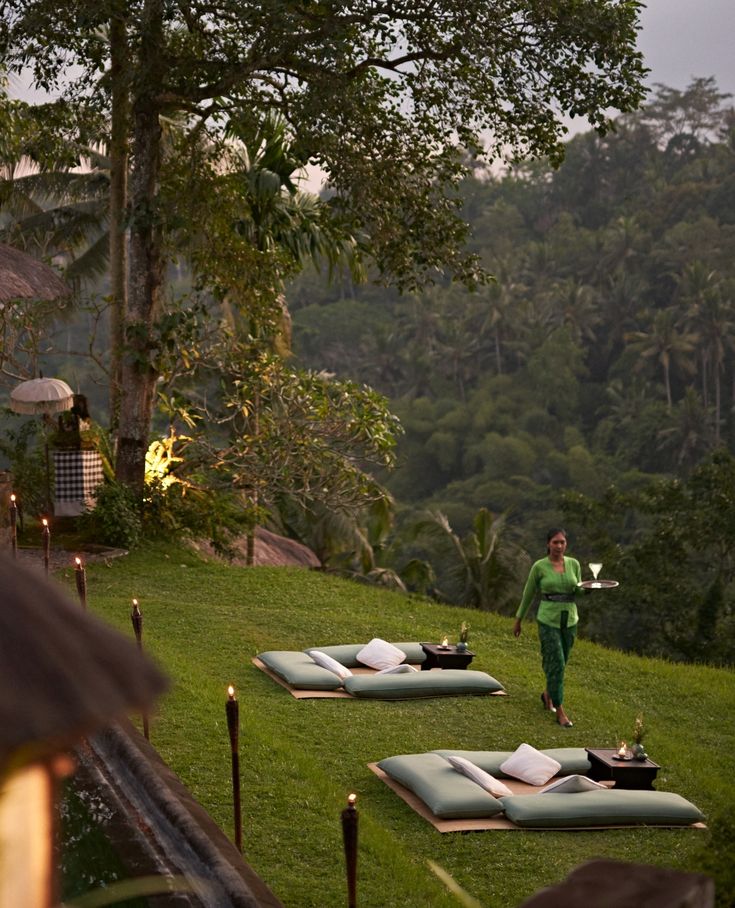 a man standing on top of a lush green field next to lots of beds covered in blankets