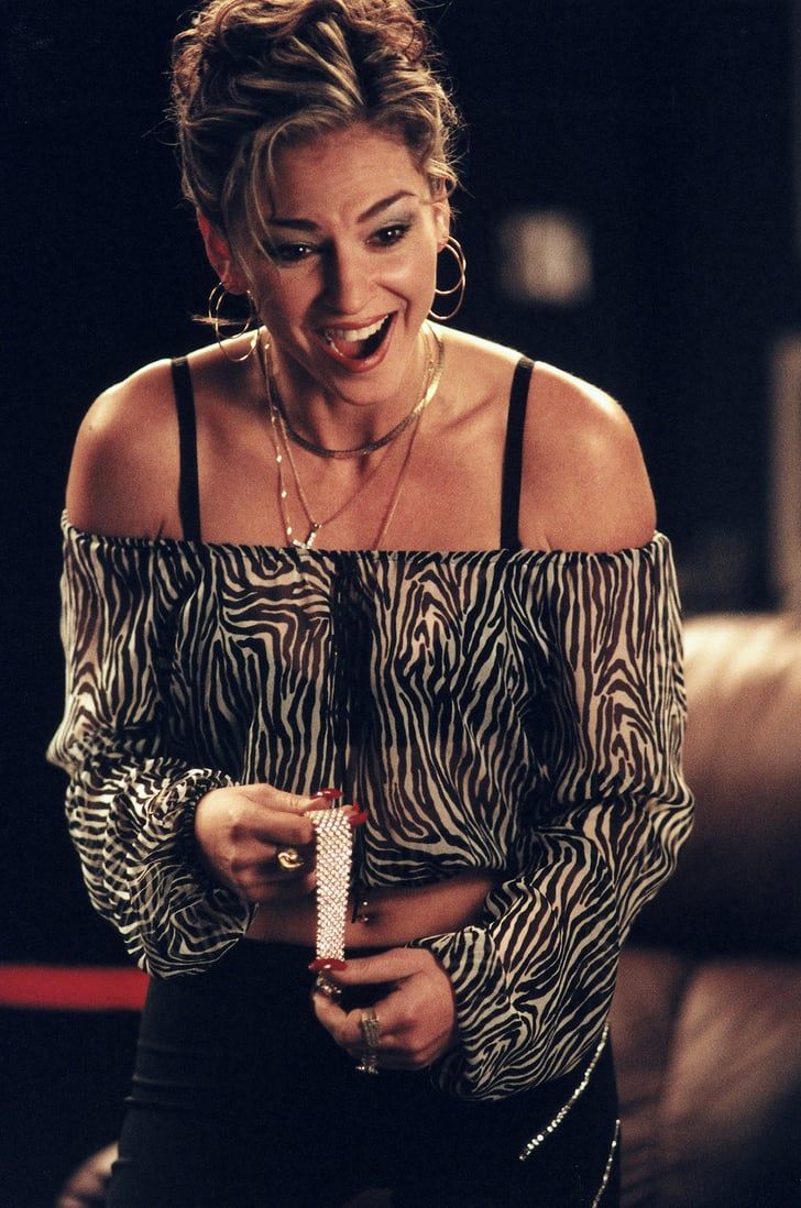 a woman laughing while holding a cell phone in her right hand and wearing an animal print top