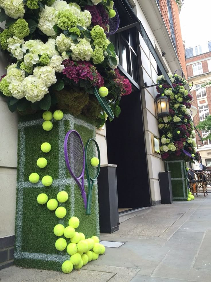 tennis balls and racquets are on display in front of a building with flowers