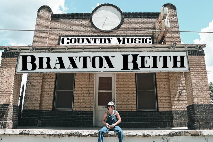 a man sitting on top of a brick building next to a large clock and the words braxton retih