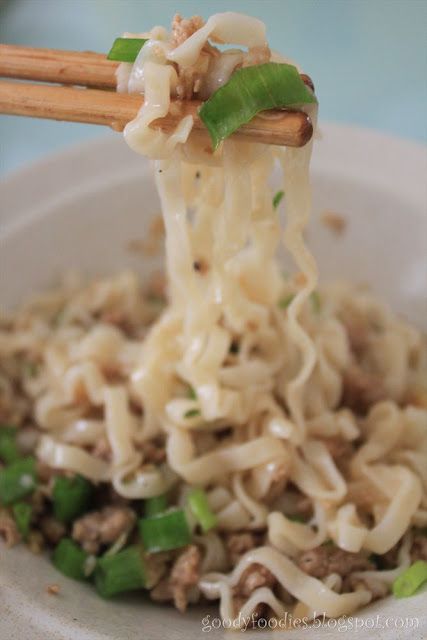 noodles with meat and vegetables being held by chopsticks