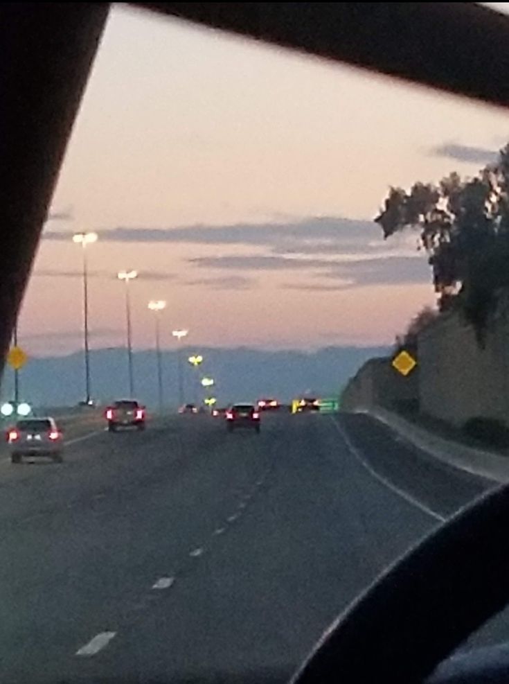 cars are driving down the highway at dusk