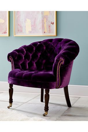 a purple velvet chair in front of two paintings on the wall with white rugs