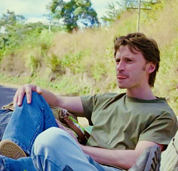 a man sitting on a bench with his legs crossed and looking off to the side