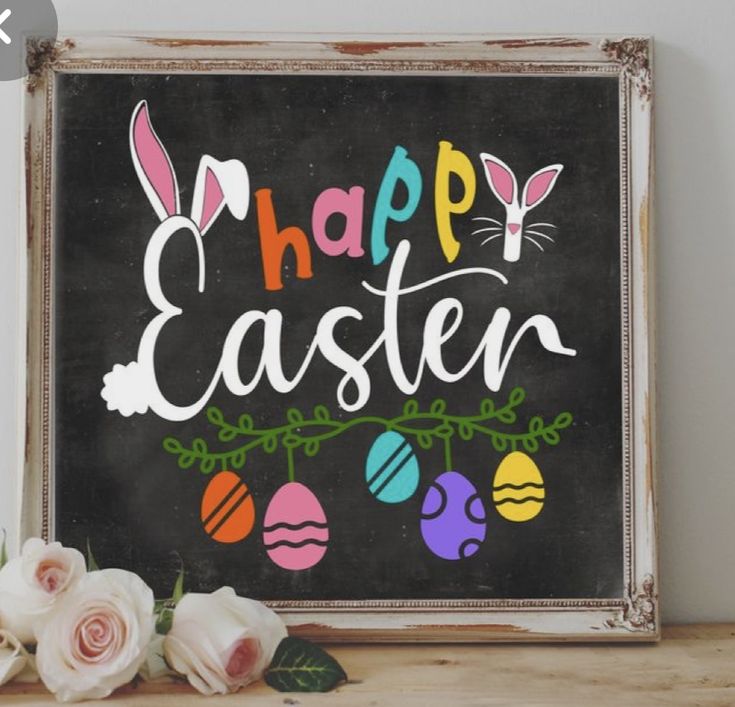 a chalkboard sign with the words happy easter painted on it next to some flowers