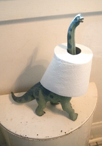 a small toy dinosaur with a roll of toilet paper on it's head