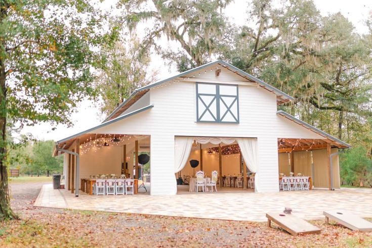 a white barn with tables and chairs set up outside