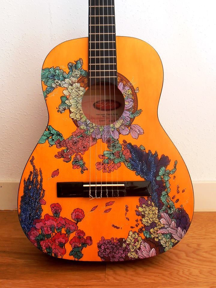 an orange guitar with flowers painted on it