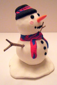 a small snowman with a hat and scarf on it's head sitting on top of a white plate