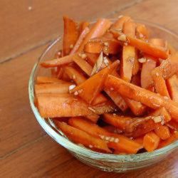 a glass bowl filled with sliced carrots on top of a wooden table