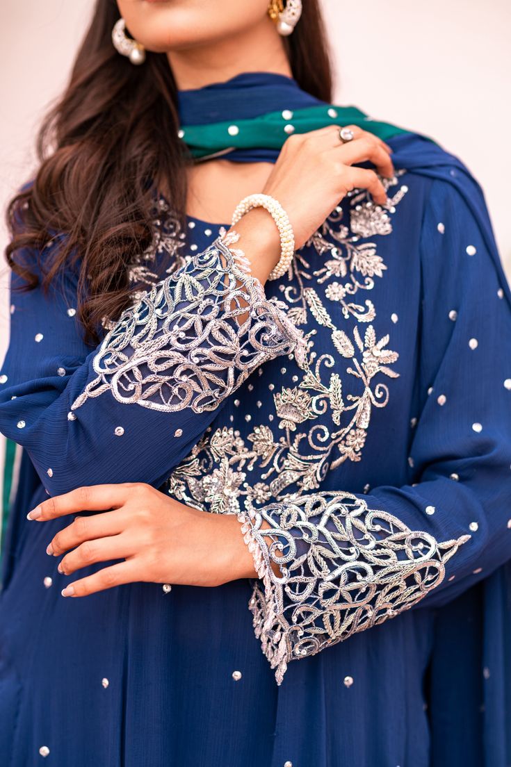 Introducing our Dark Blue Long Shalwar Kameez, featuring exquisite zari, sequins, naqshi, kora, and dabka work on the neckline and sleeves. The cutwork embroidery with crystal drops adds a touch of elegance, while the fabric and silk lining provide comfort. The navy blue chiffon dupatta with a silver sequin chhan and contrasting sea green silk border completes the look. Semi-stitched Blue Salwar Kameez With Intricate Embroidery, Blue Chinon Lawn Suit For Festive Occasions, Festive Blue Chinon Lawn Suit, Bollywood Style Blue Lawn Suit With Mirror Work, Elegant Blue Chinon Lawn Suit, Blue Georgette Lawn Suit For Festivals, Blue Bollywood Lawn Suit With Traditional Drape, Blue Lawn Suit With Dabka For Party, Blue Anarkali Lawn Suit For Wedding