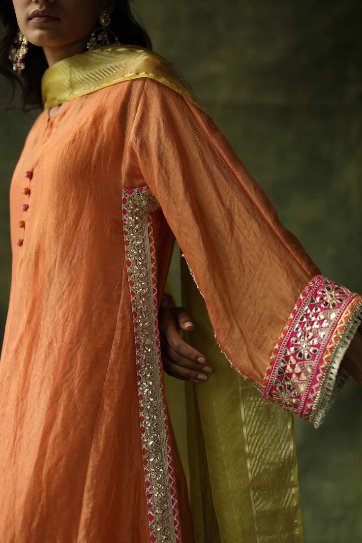 Editor's Note A Contrast Kurta Set In Chanderi Silk With Gota Embroideries On The Sides, Sleeves And The Ghera. The Pants Are A Contrast Pop With Hand Embroidered Floral Bootis. The Dupatta With Hand Made Tassels Add A Further Festive Pop To The Outfit. Color: Burnt Orange Fabric: Chanderi Silk Kurta, Modal Satin Lowers, Satin Slip Organza Dupatta Care: Dry Clean Only Disclaimer: The actual colour of the outfit may differ slightly than the image shown owing to different monitors and photography Pakistani Fashion Party Wear, Salwar Kamiz, Traditional Indian Outfits, Kurti Neck Designs, Kurta Designs Women, Designer Dresses Casual, Boutique Dress Designs, Fancy Dress Design, Stylish Dress Book