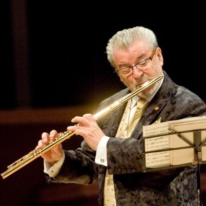 an older man playing the flute on stage