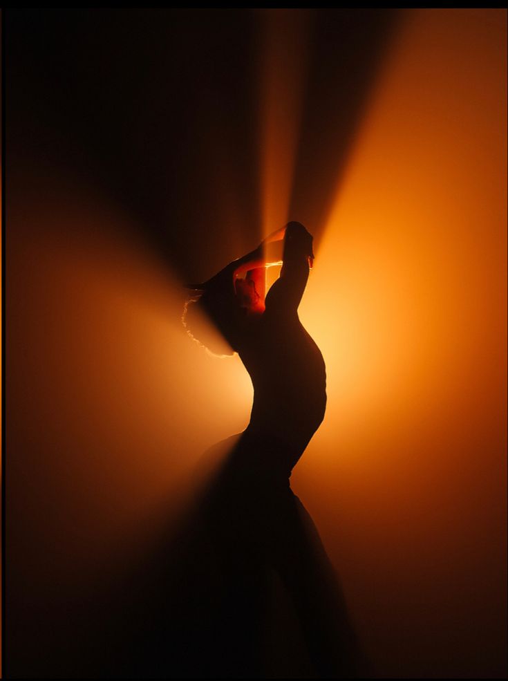 a woman is dancing in the dark with light coming through her