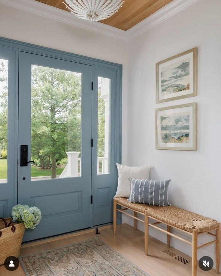 a blue front door with a bench and two pictures on the wall