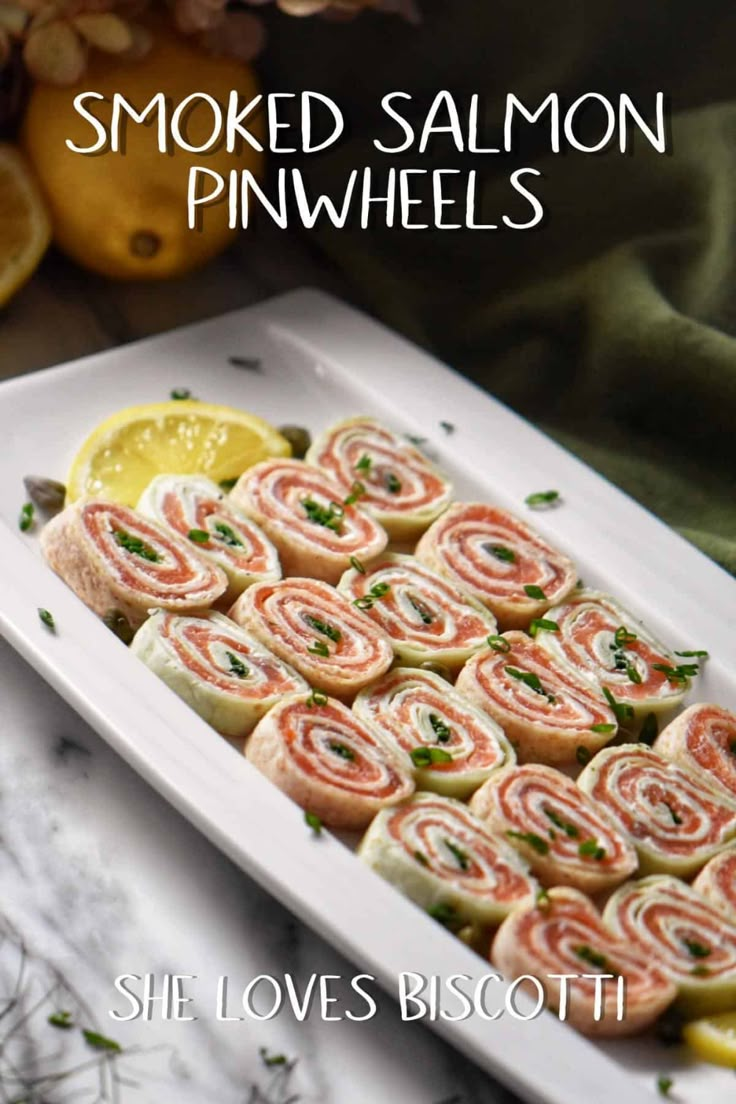 smoked salmon pinwheels on a white platter with lemon wedges