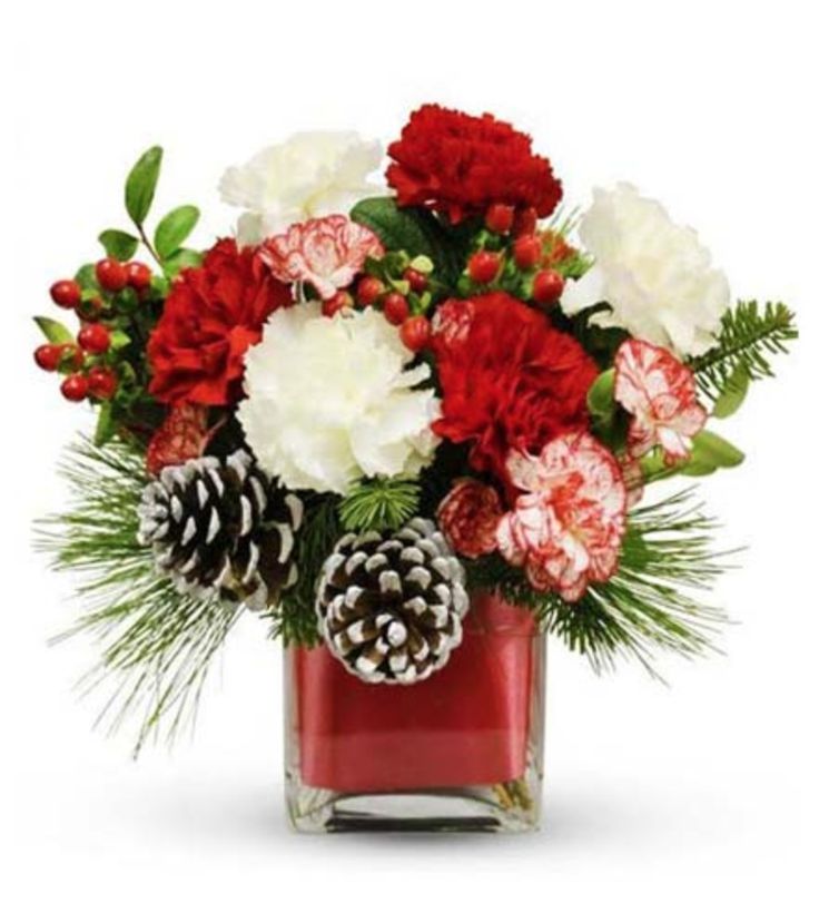 a vase filled with red and white flowers next to pineconis, berries and greenery