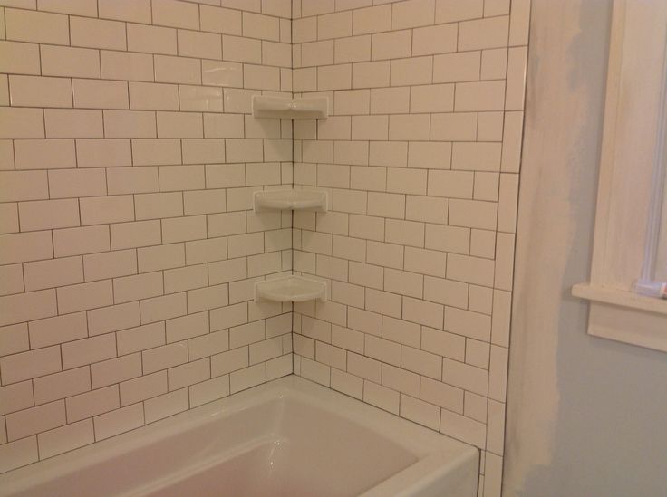 the corner of a bathroom with a bathtub and shelves