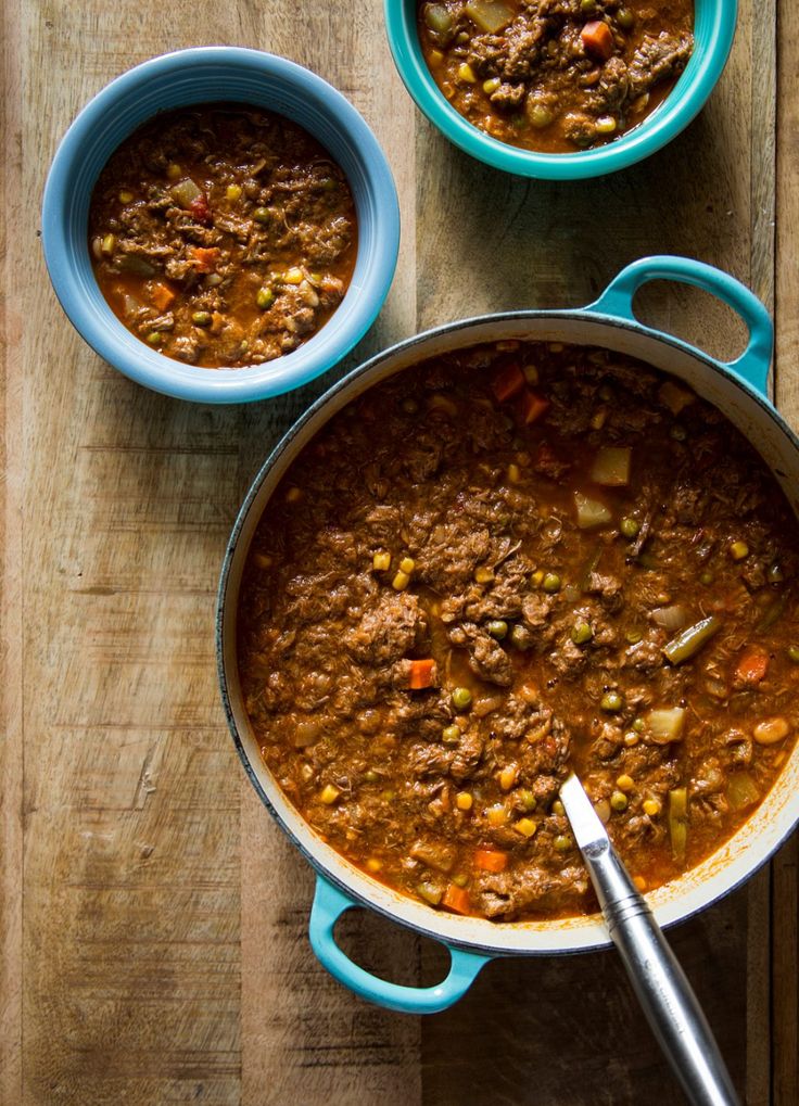 two bowls of chili on a wooden table