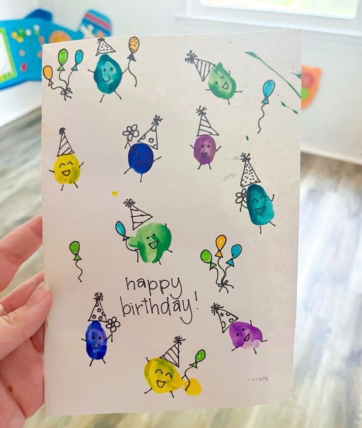 someone holding up a birthday card with balloons on it