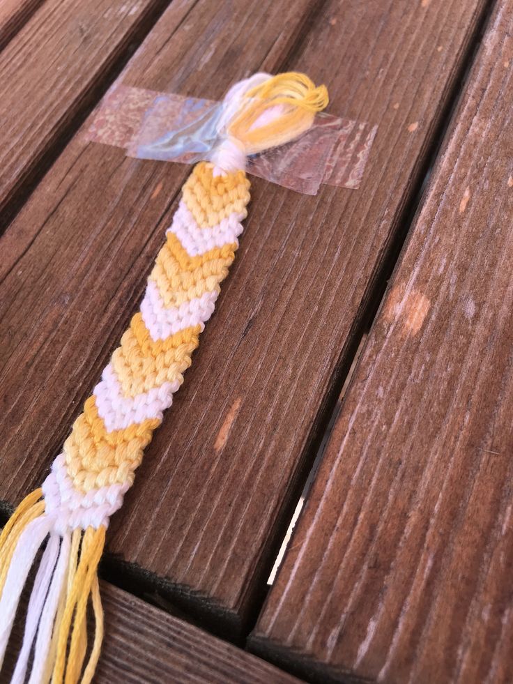 a yellow and white crocheted tassel on a wooden table with string attached to it